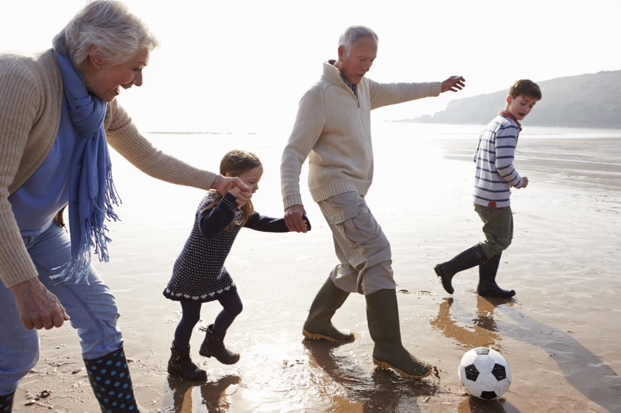 trust lawyer with grandparents playing soccer with grandkids on a beach